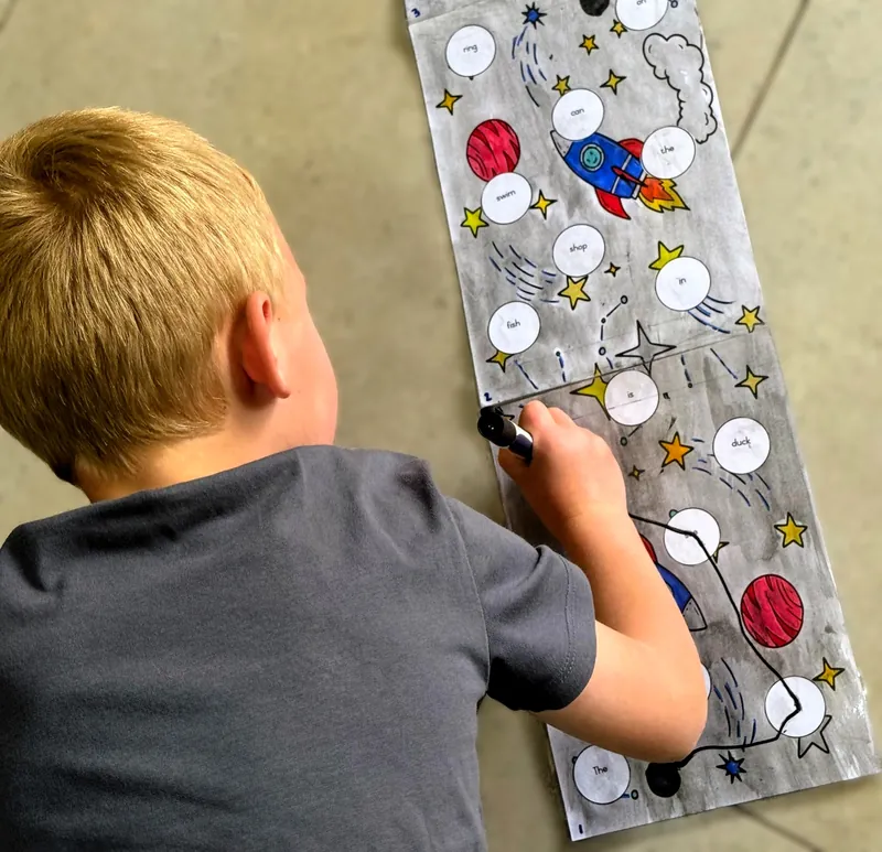 A boy joins words on a space-themed board to build a sentence